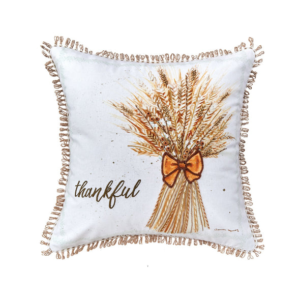 White pillow featuring an embroidered bundle of wheat with the word Thankful stitched in script